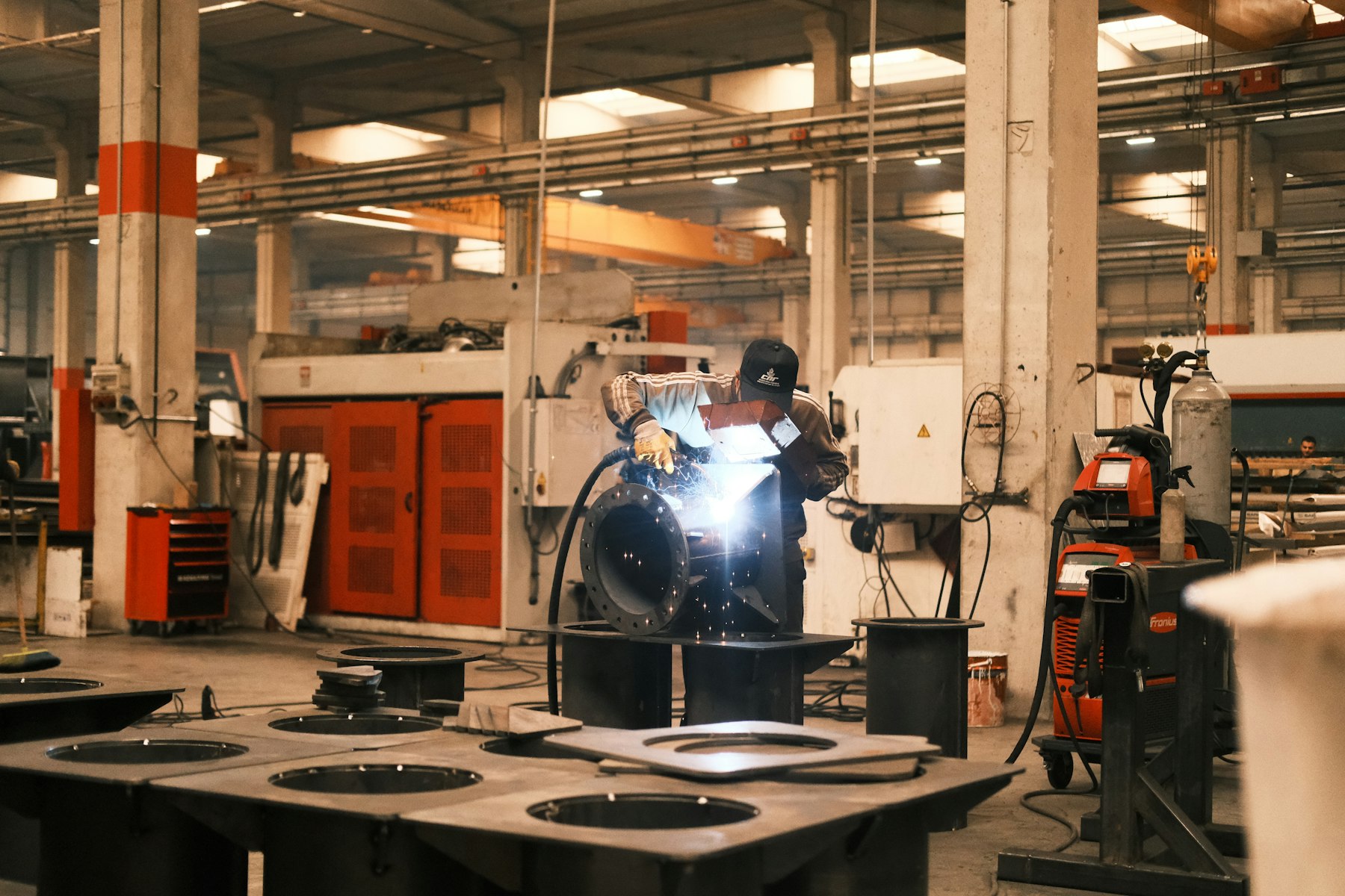 A welder fabricating a steel component on a factory floor